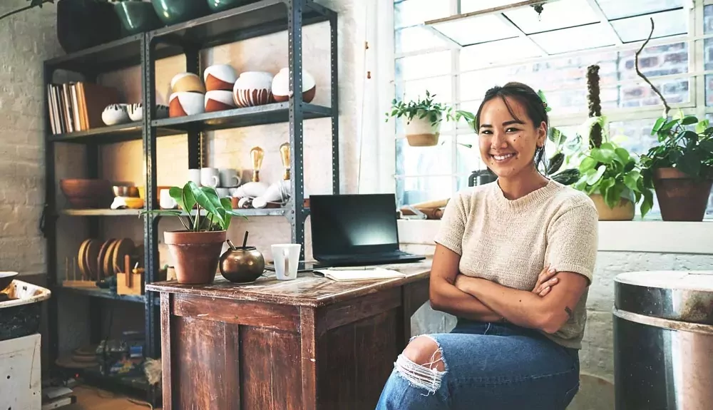 création et reprise d'entreprise - Une jeune femme assise devant le Contoire de son commerce